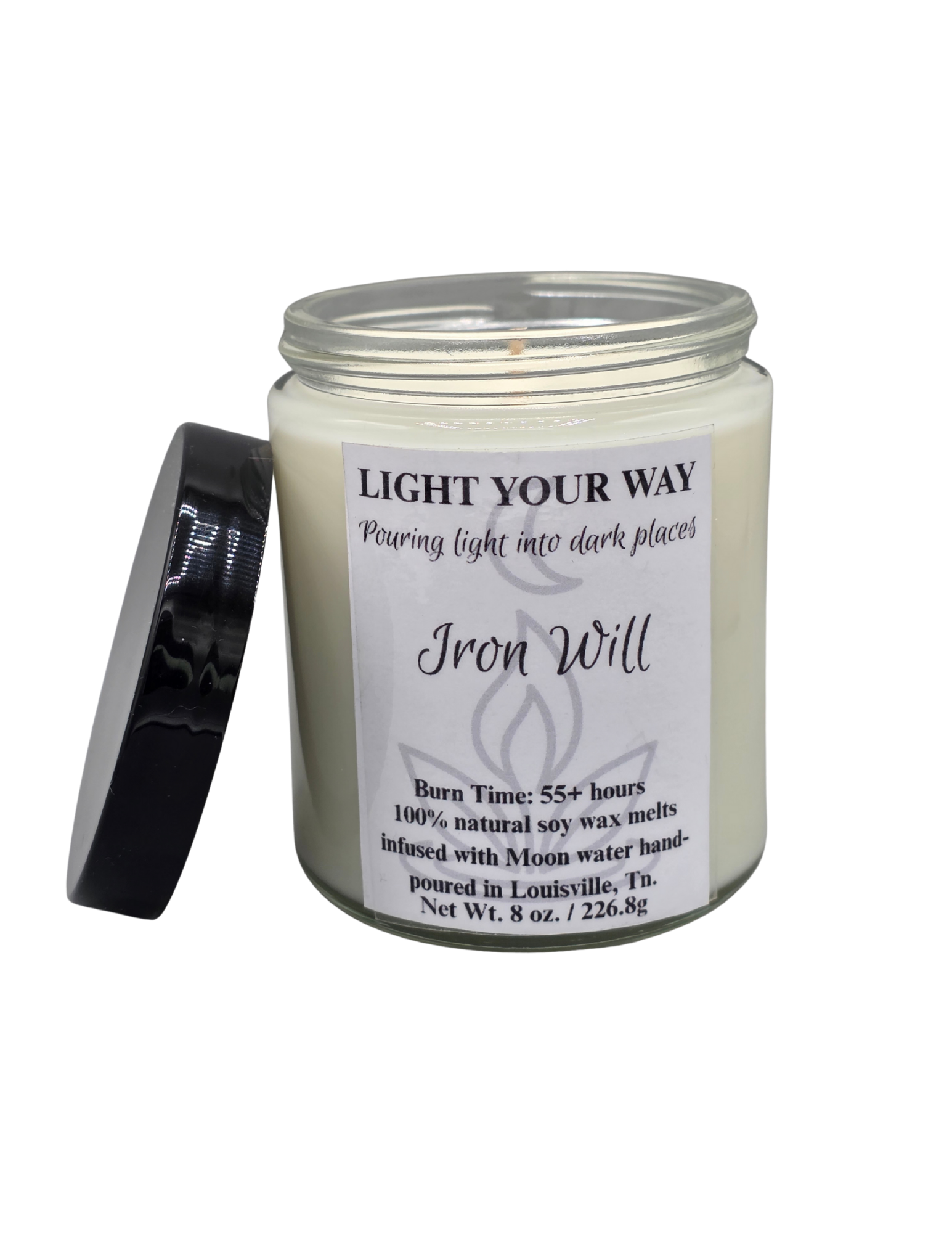 Candle jar labeled 'Iron Will' with a white label and lack plastic lid propped on the side of the clear jar