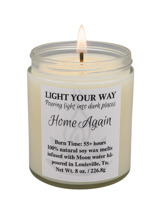 Candle in a glass jar with a home again label on a white background