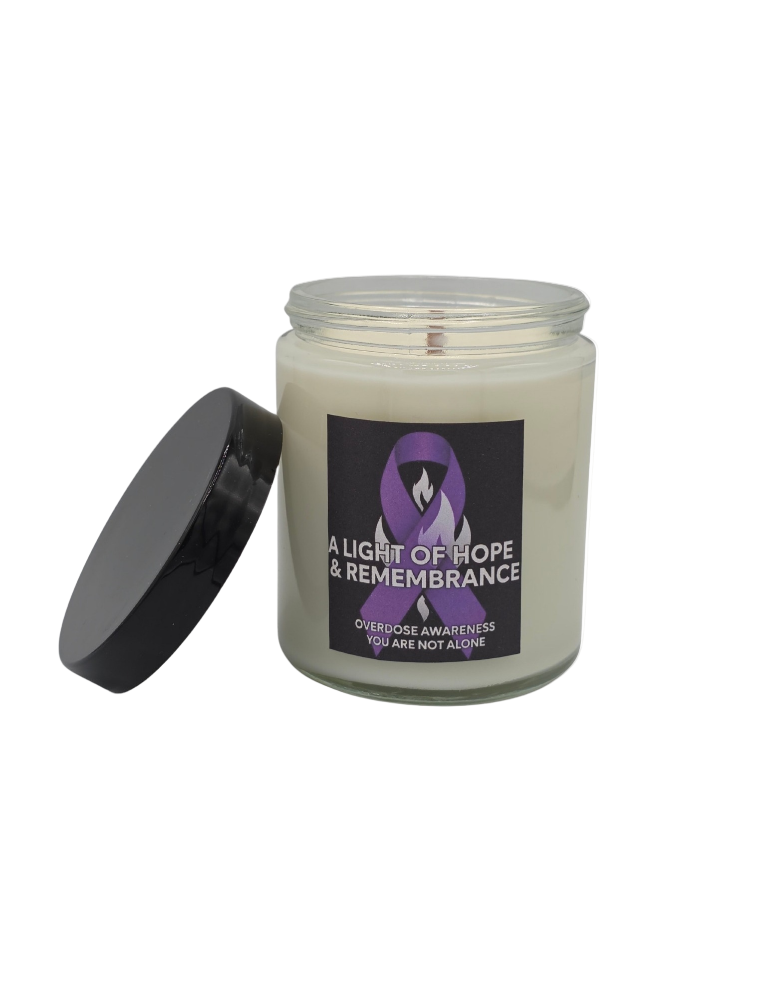 Candle with a purple awareness ribbon label and a black lid on its side on a white background